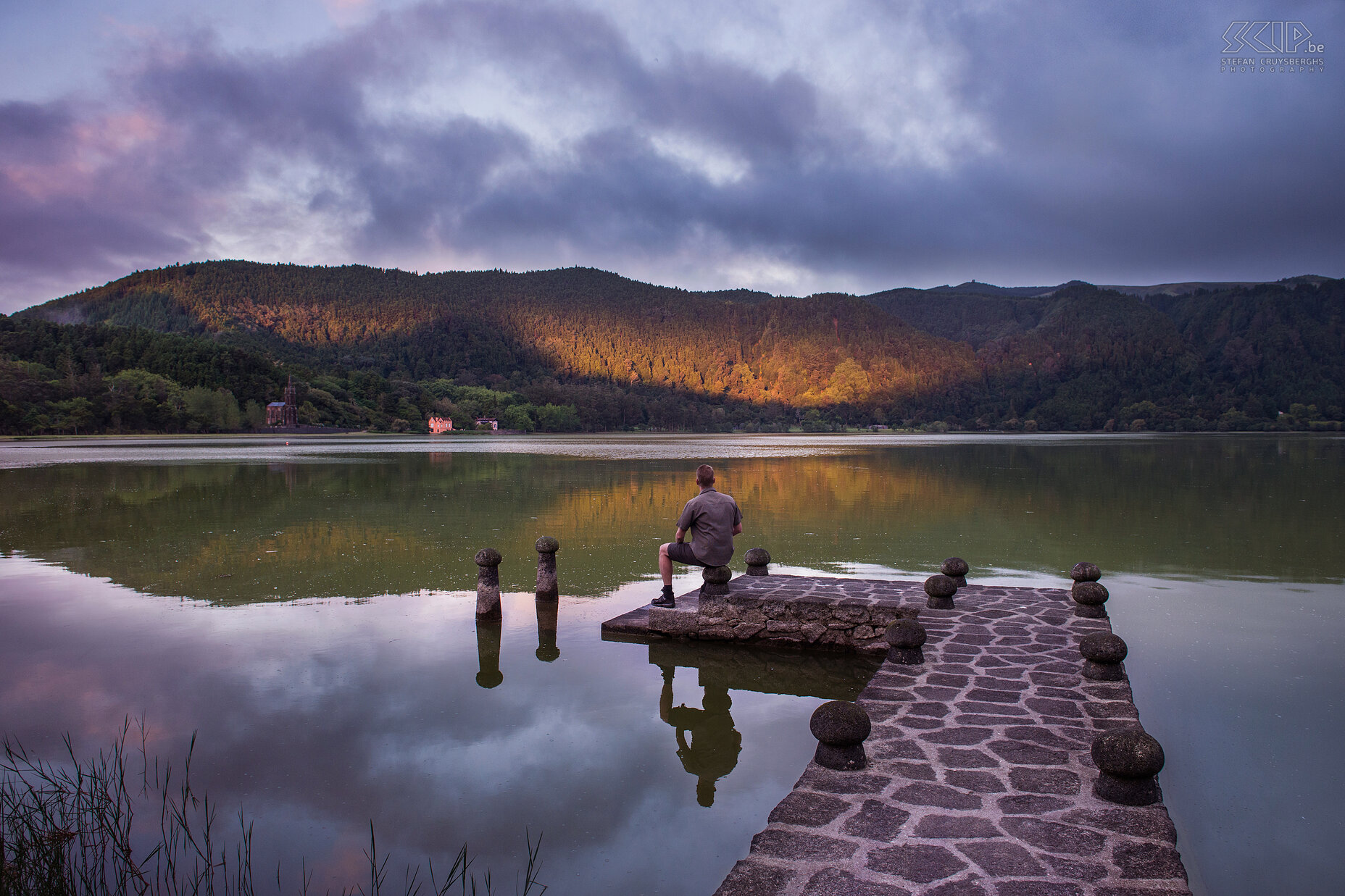 Lagoa das Furnas - Stenen pier 'Selfie' tijdens zonsopkomst op de stenen pier in het meer van Furnas op het eiland São Miguel. Lagoa das Furnas is een kratermeer en in de omgeving zijn er 2 calderas. Furnas ligt in een van de drie actieve vulkanen op het eiland São Miguel. Aan de overkant van het meer ligt de neogotische Capela de Nossa Senhora das Vitórias (einde 19e eeuw), een miniatuur versie van de kathedraal van Chartres.<br />
 Stefan Cruysberghs